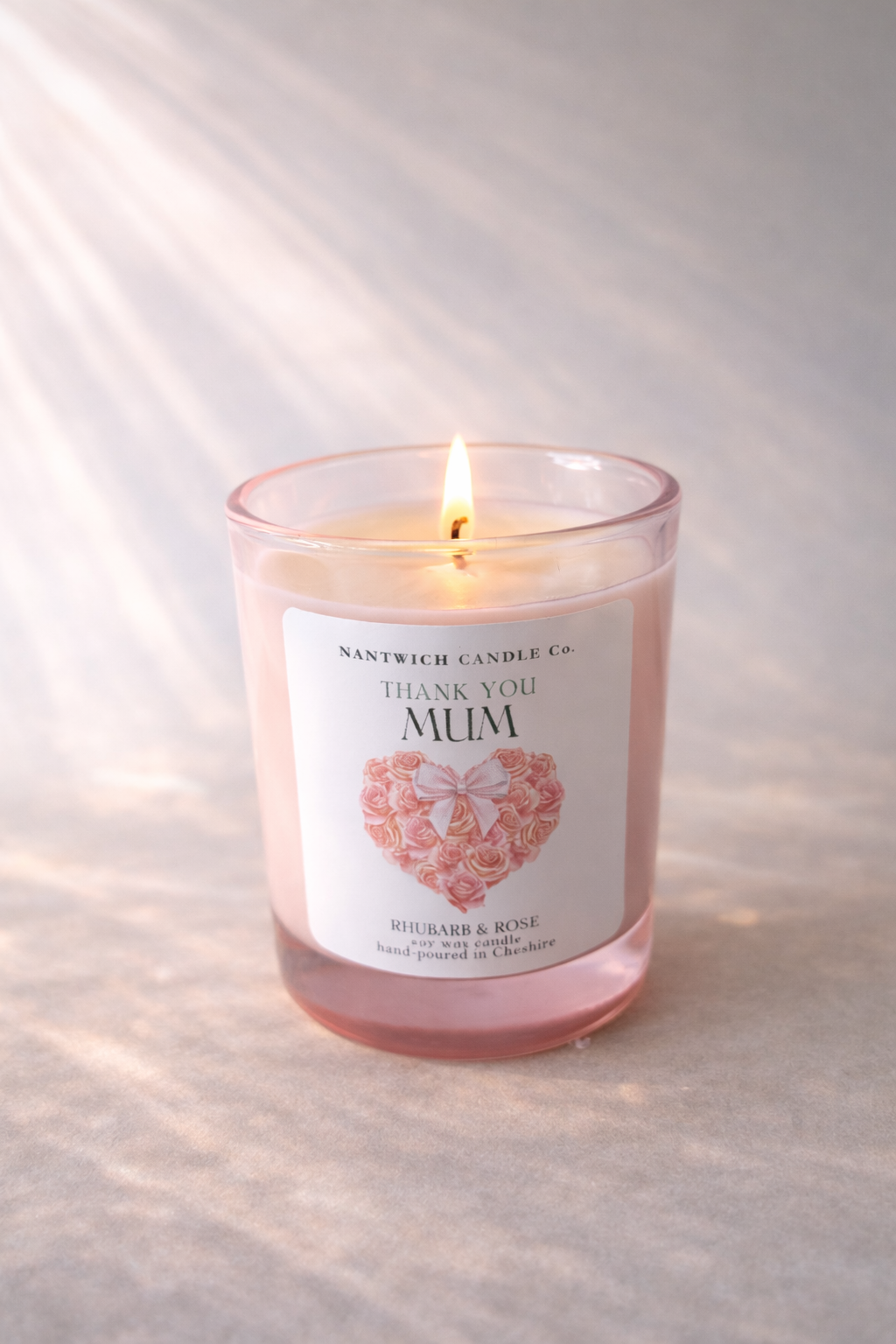 Mothers Day Rhubarb & Rose Scented Soy Wax Candle in pink holder with flame, labeled 'Thank you Mum'.